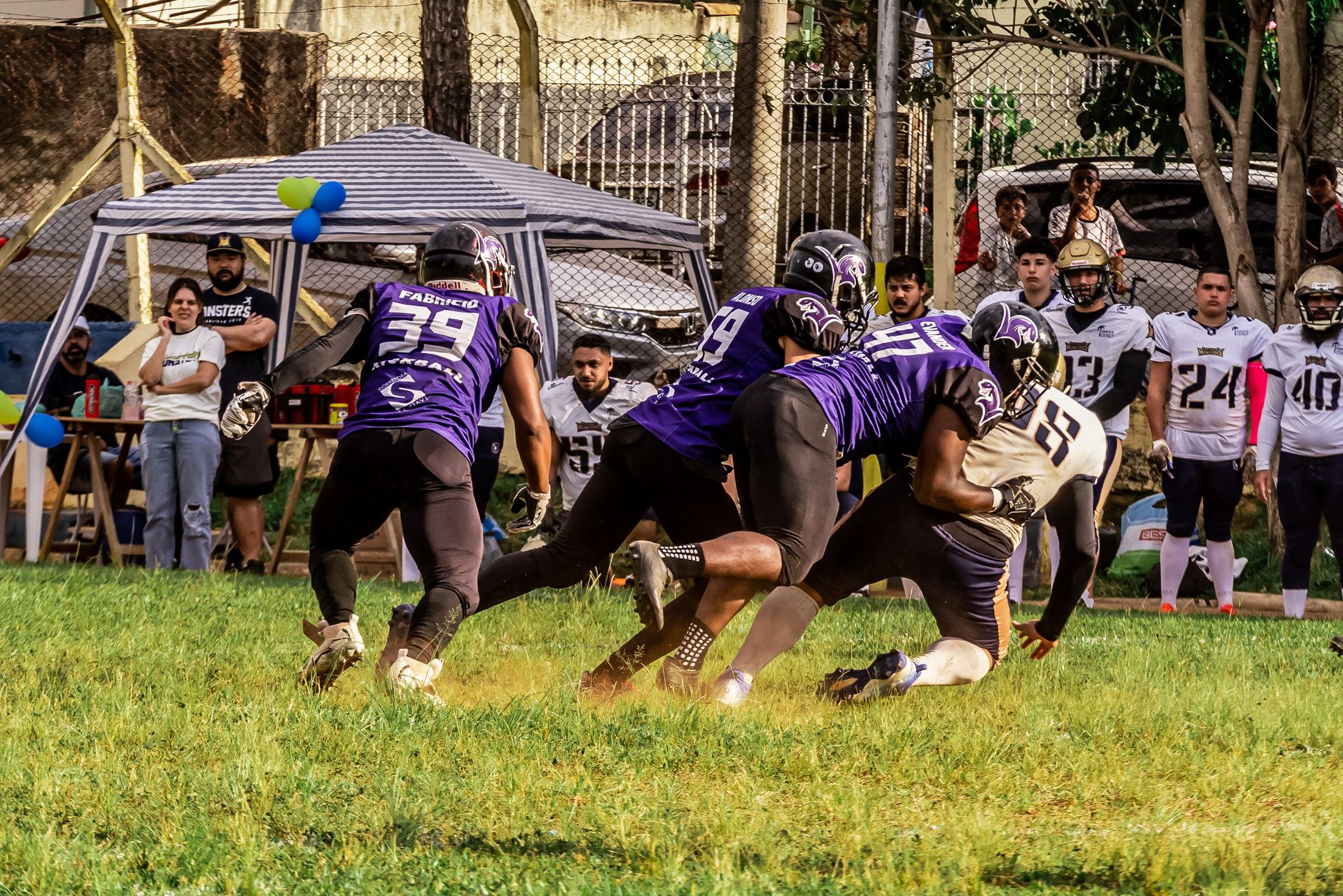 Players in action at an American football match with spectators cheering outdoors.