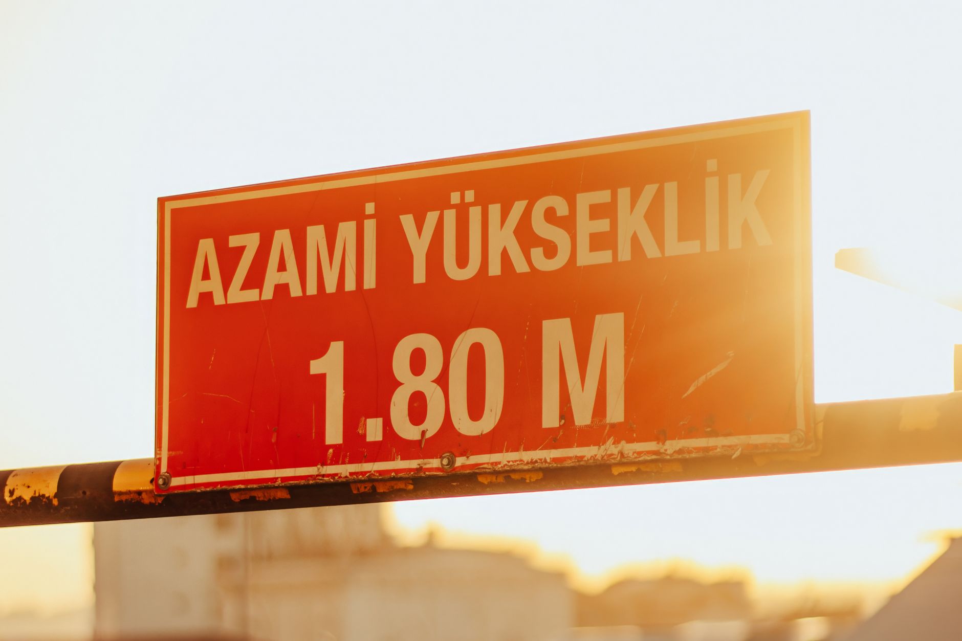 A red maximum height sign with sunlight in the background, reading 'Azami Yukseklik 1.80 M'.