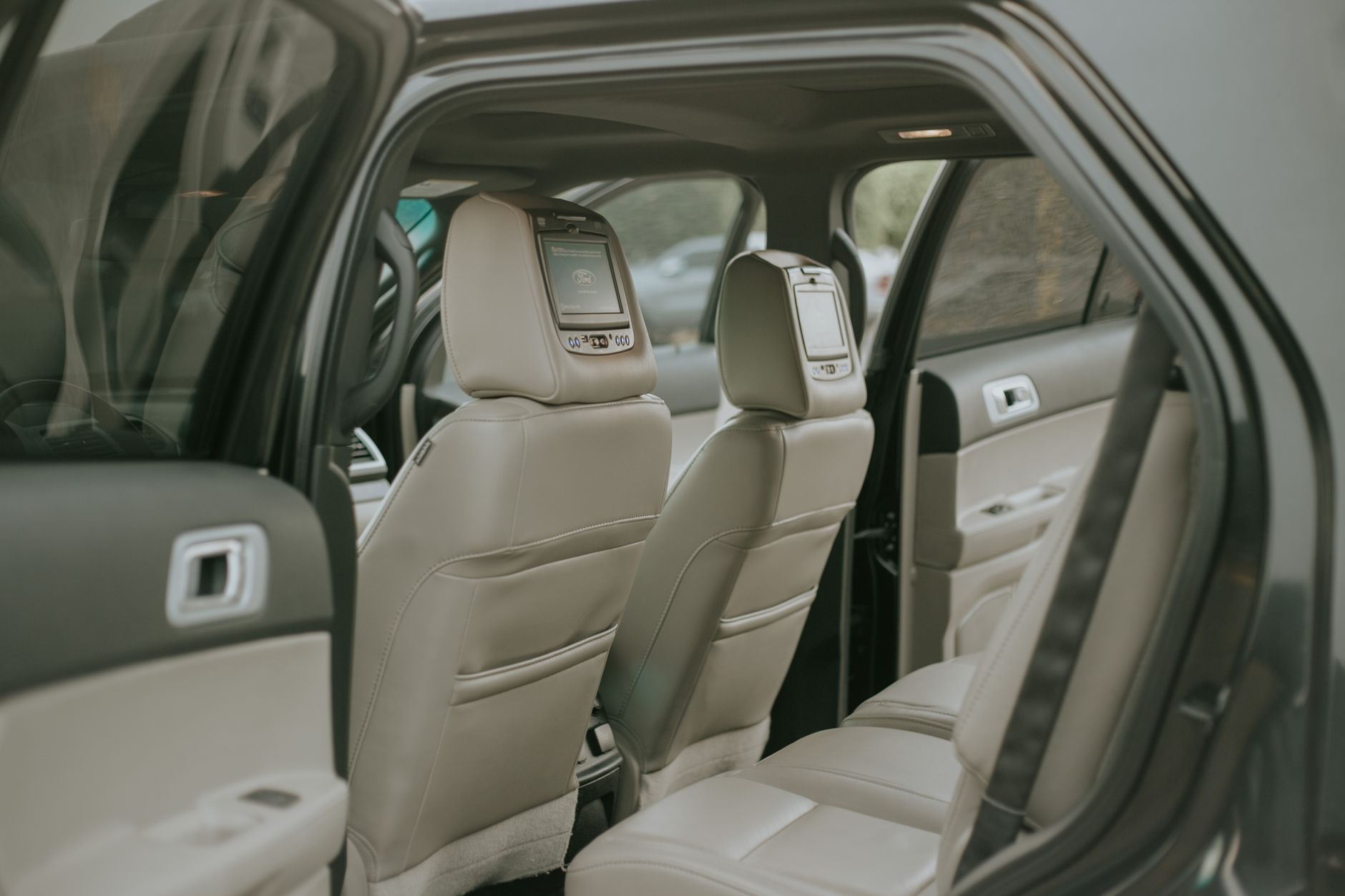 Explore the elegance of a modern car interior featuring plush leather seats and built-in screens for ultimate comfort.