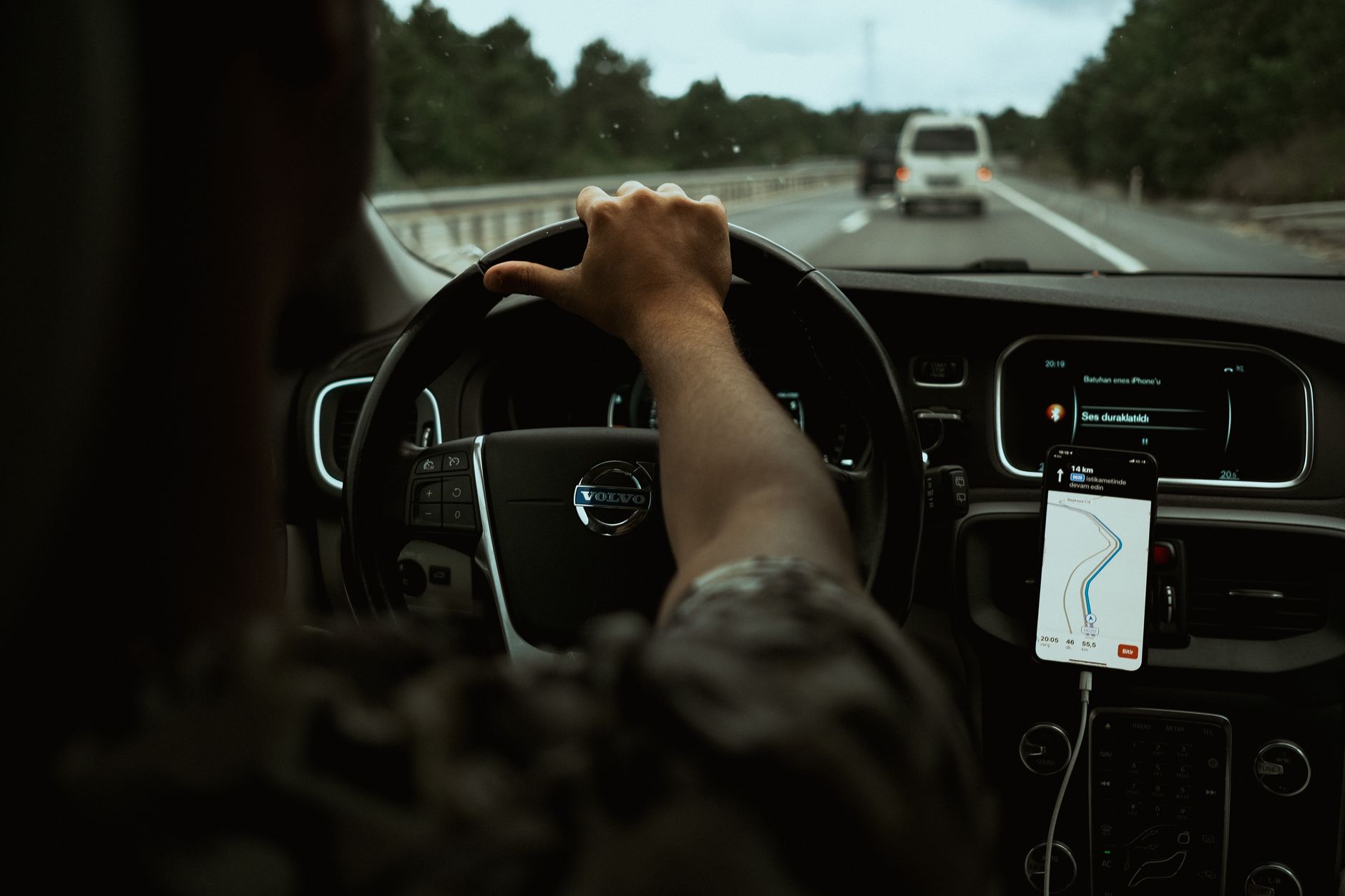 A driver navigates the highway with a smartphone GPS, showcasing modern car interior design.