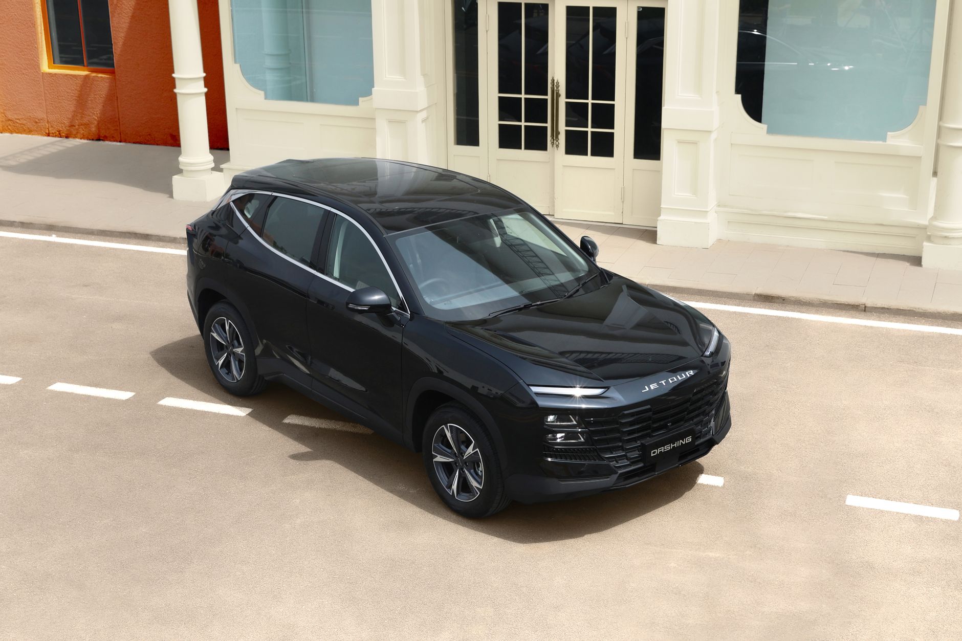 Modern black SUV parked on a sunny city street with stylish architecture background.