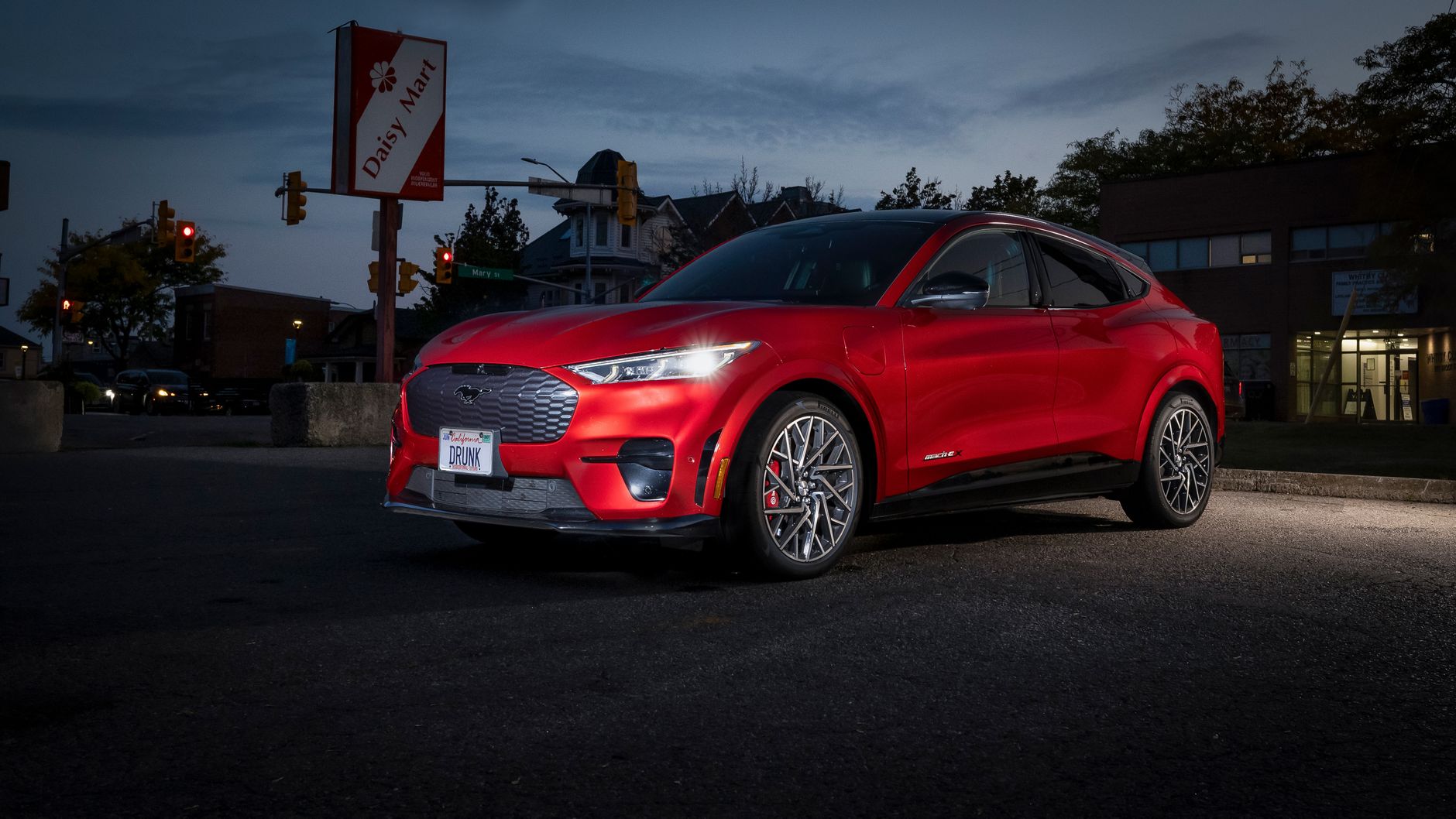 Red Ford Mustang Mach-E electric SUV parked at night in an urban setting.