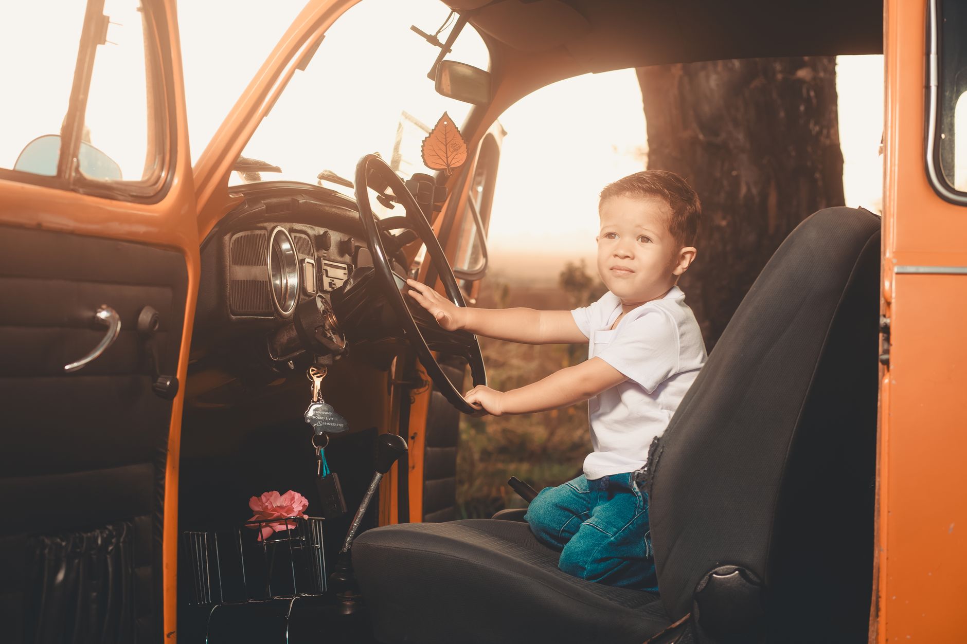 Child sits in vintage car, looking out, learned driving fun.