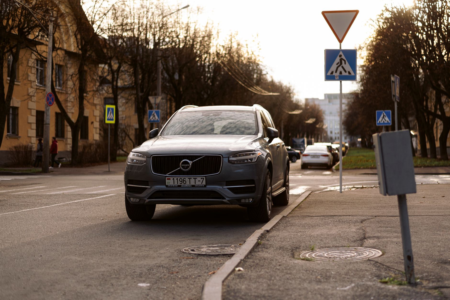 A Volvo XC90 parked on a city street surrounded by road signs. Urban setting with natural daylight.