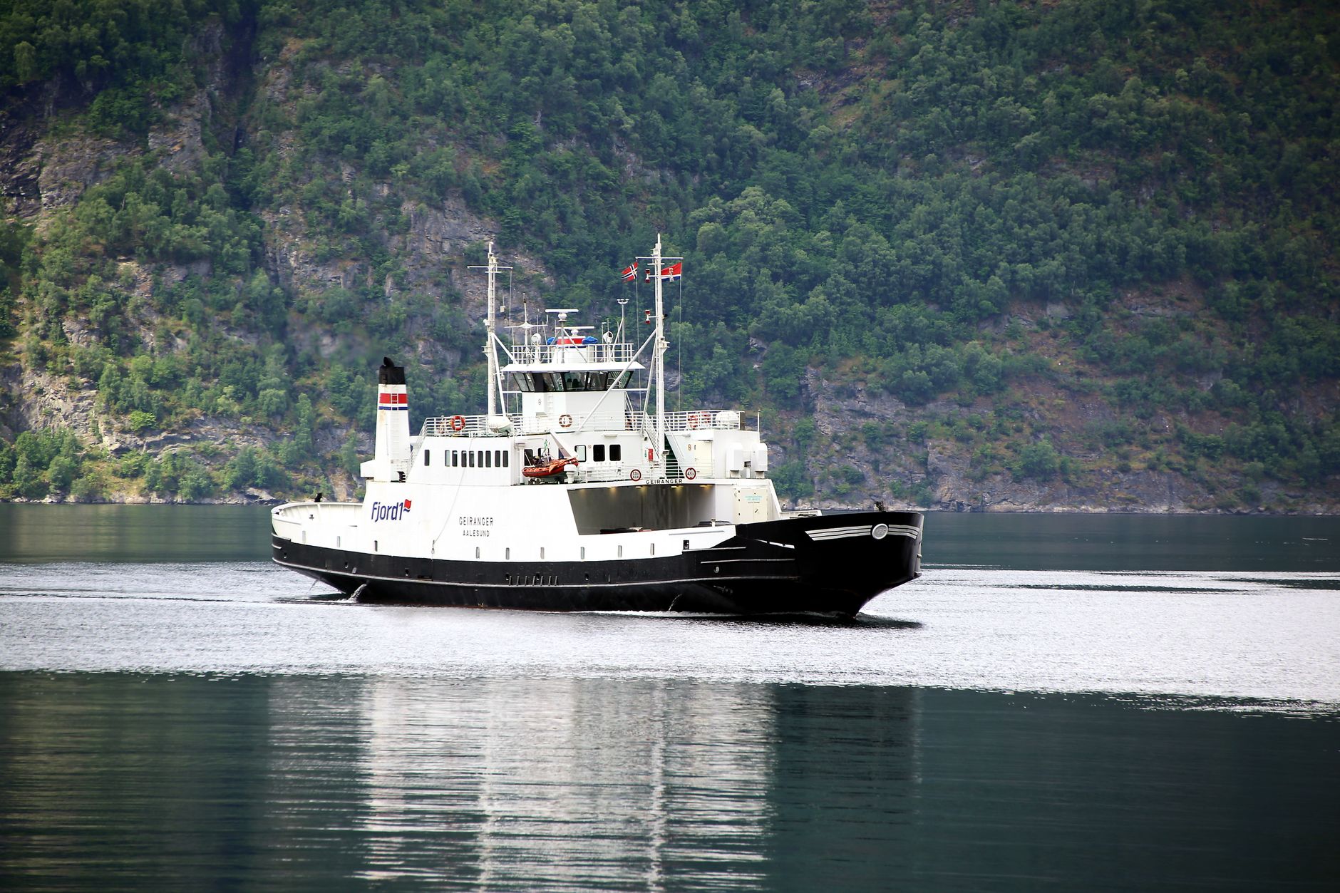 Ferry travels across a stunning Norwegian fjord amidst beautiful natural scenery.
