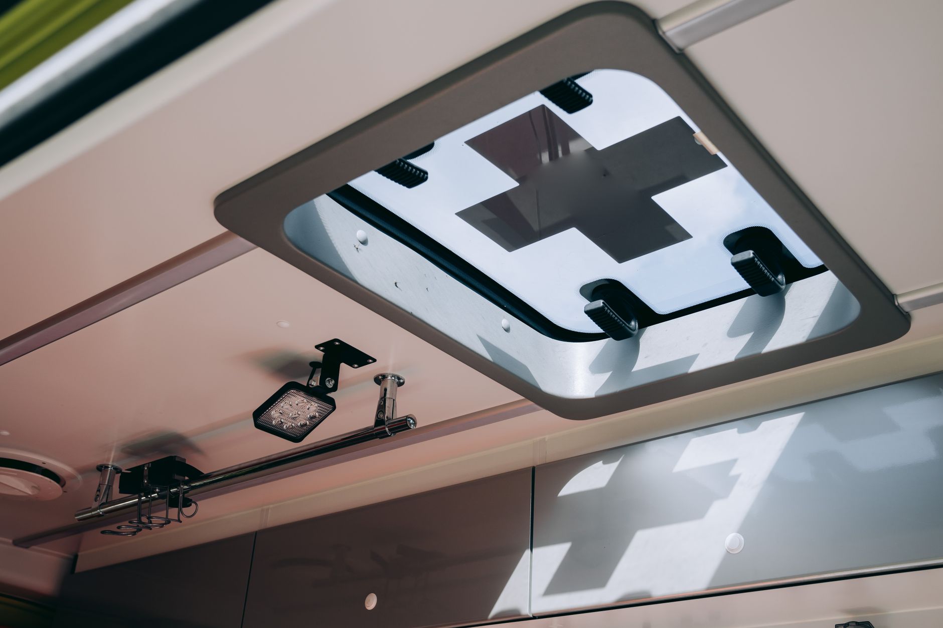 View of an ambulance's roof window featuring a medical cross symbol and ceiling equipment.