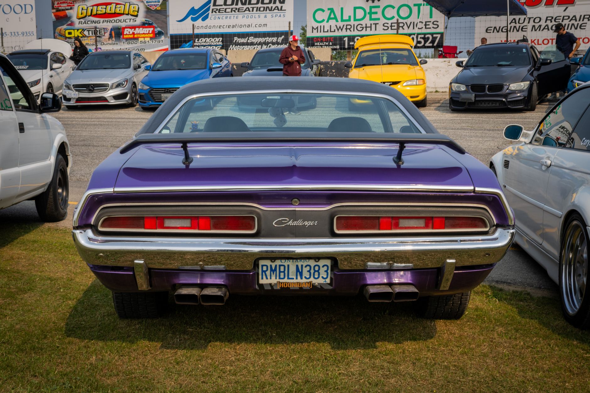 Classic Dodge Challenger in vibrant purple displayed at outdoor car show.
