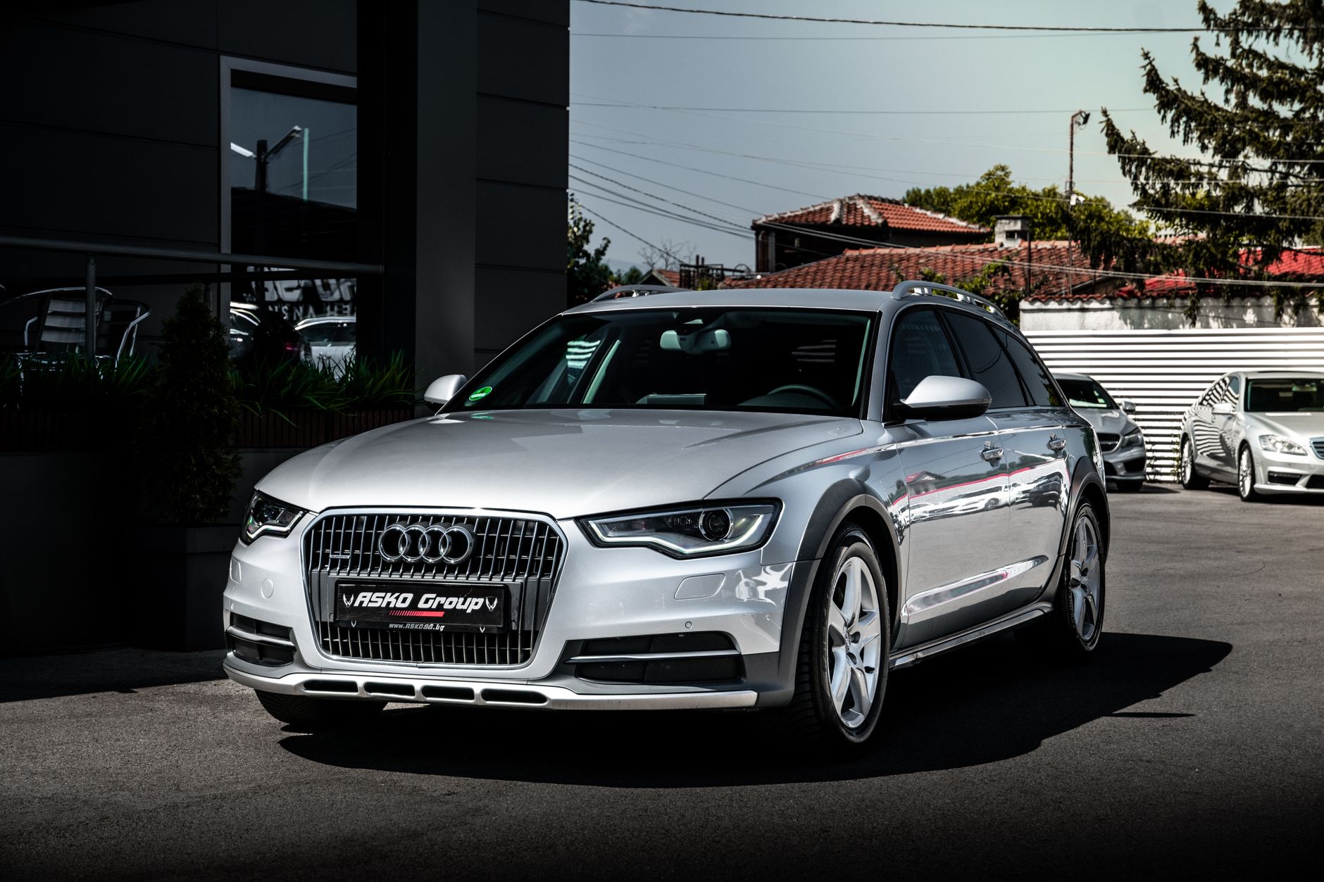 A sleek silver Audi A6 parked in a modern urban setting, showcasing stylish design and contemporary architecture.
