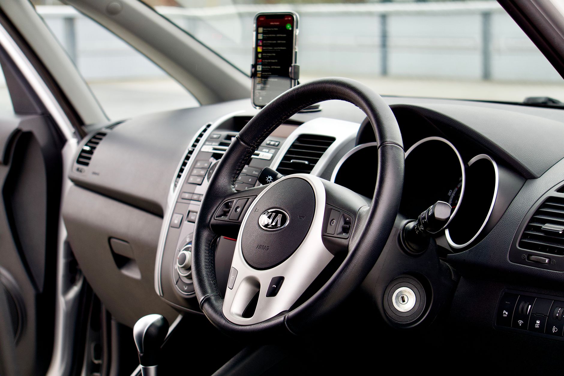 Close-up of a modern car interior featuring a dashboard, steering wheel, and smartphone mount.