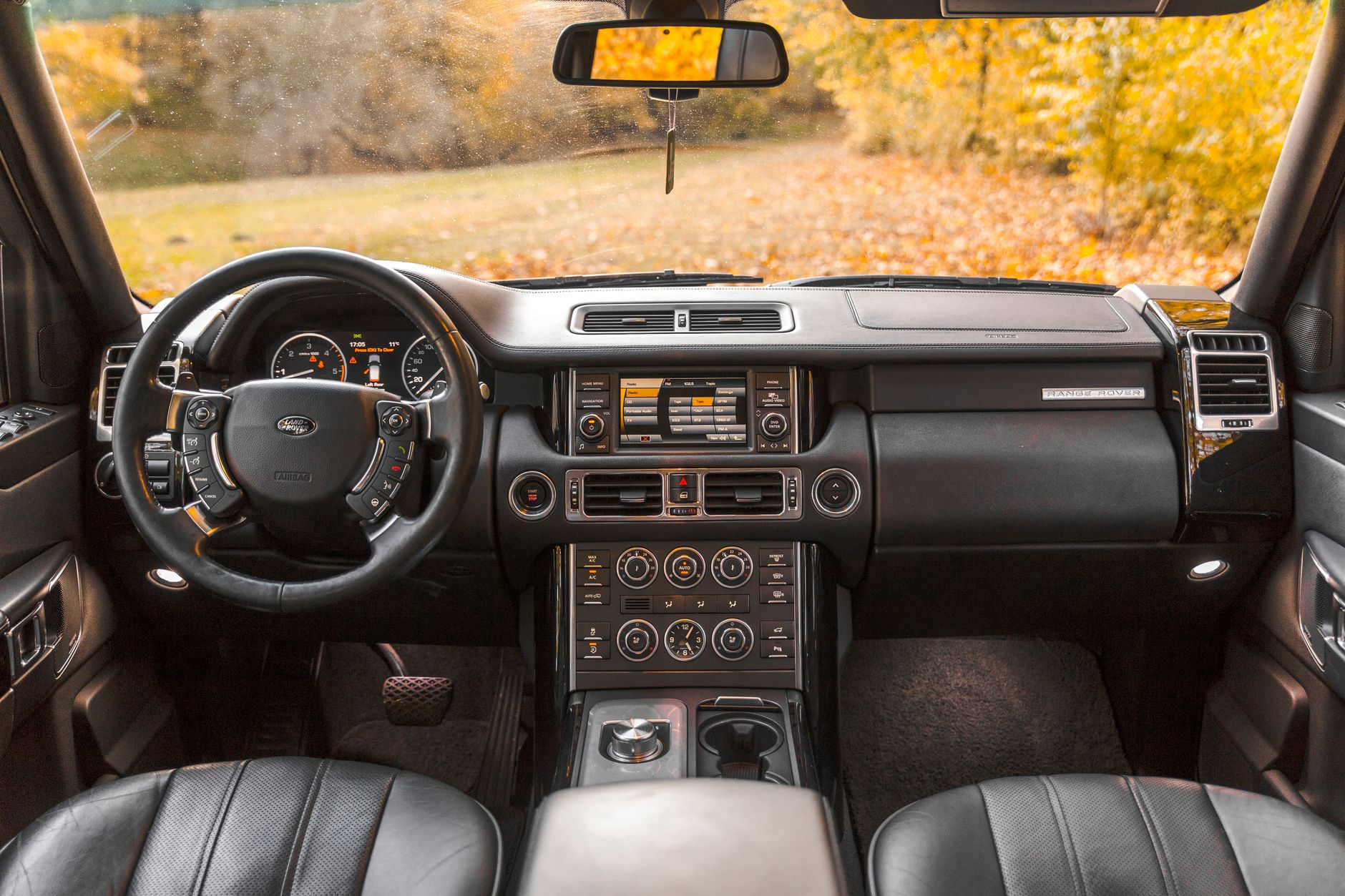 Elegant Range Rover interior showcasing modern design and leather seats, captured in autumn light.