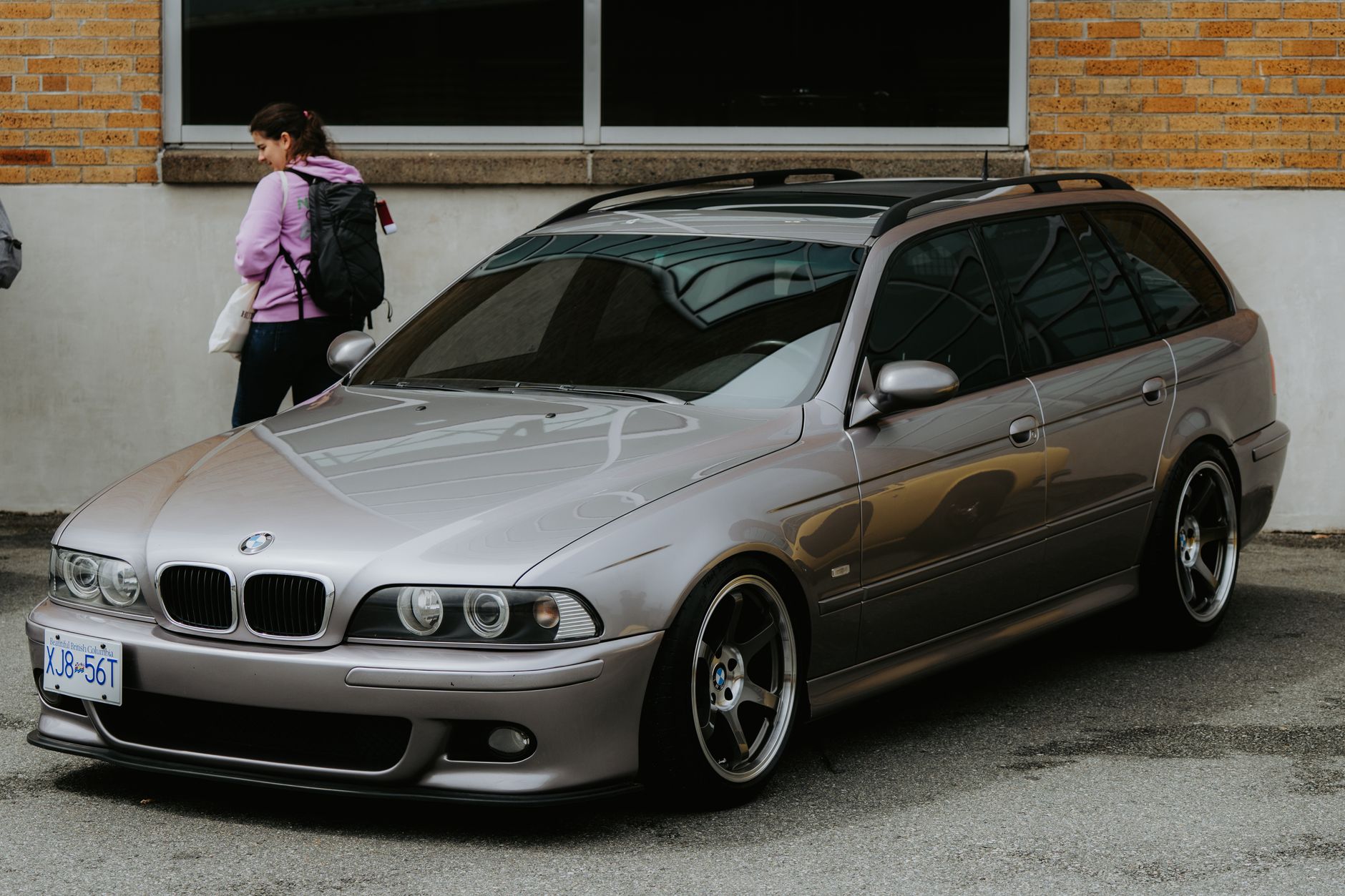 A stylish metallic station wagon parked on an urban street with a pedestrian passing by.