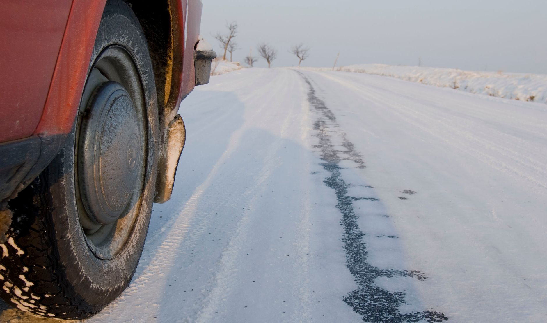 Close-up of a car tire on a snow-covered road in a winter landscape.