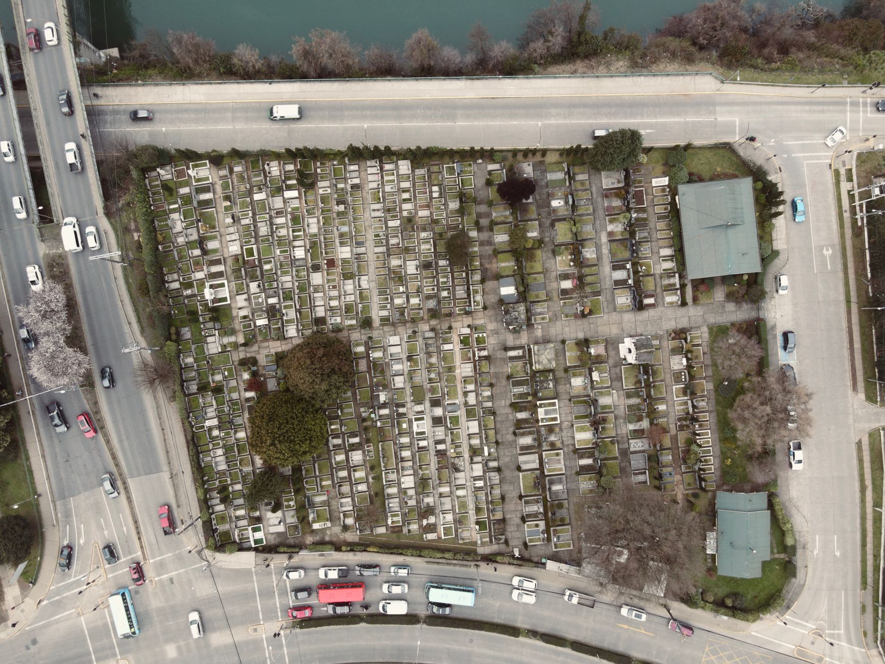 Top view of a cemetery beside a busy street intersection in a city landscape.